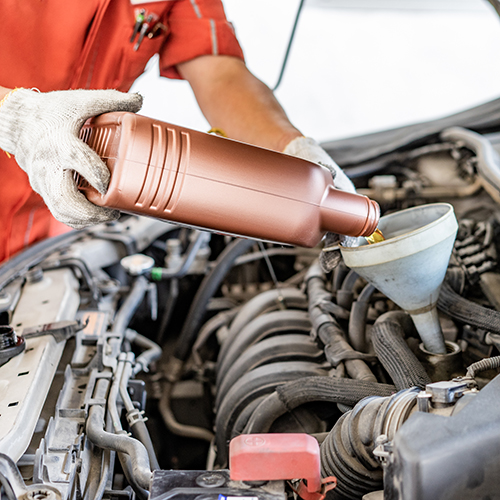 Car mechanic pouring fresh oil into engine